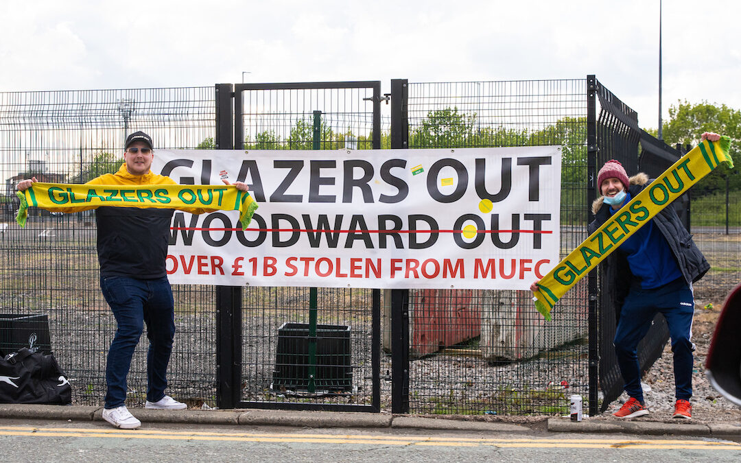 Two Manchester United supporters protest against the owners with "Glazers Out" scarves and banner outside the ground before the FA Premier League match between Liverpool FC and Manchester United FC at Old Trafford which was postponed due to safety concerns after a number of supporters entered the stadium.